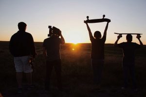 group of people holding skateboards under sunset